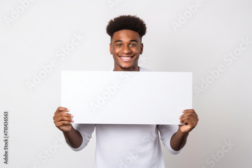 Happy young black man holding blank white banner sign, isolated studio portrait.