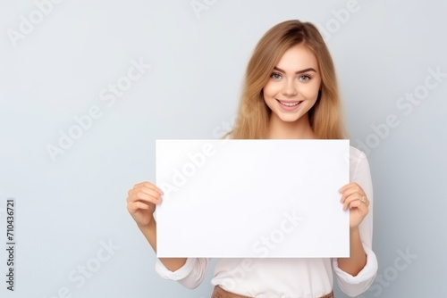 Happy young woman holding blank white banner sign, isolated studio portrait .