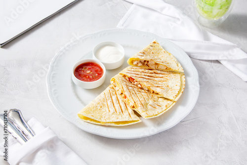 Quesadilla with cheese and chicken, with red and white sauce on a plate