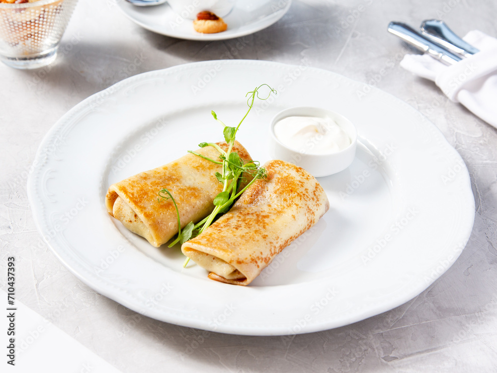Pancakes with filling on a white plate in a cafe, restaurant. Pancakes with filling on a white plate in a cafe, restaurant.