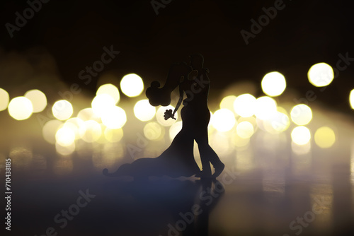 Black silhouettes of pair dancers performing. Man and woman are dancing on gray background with white backlight. Choreography. New Year's ball photo