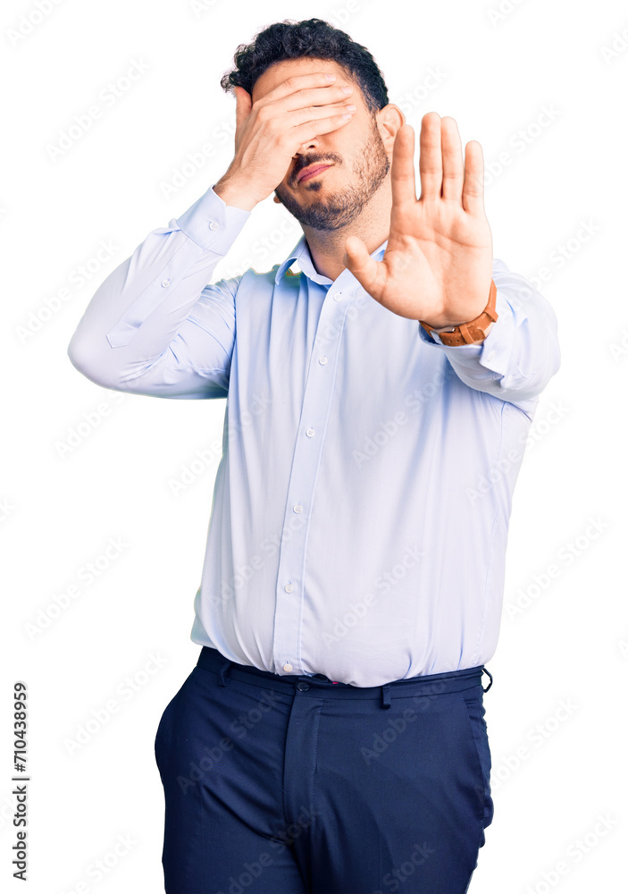 Young hispanic man wearing business clothes covering eyes with hands and doing stop gesture with sad and fear expression. embarrassed and negative concept. Young hispanic man wearing business clothes covering eyes with hands and doing stop gesture with sad and fear expression. embarrassed and negative concept.