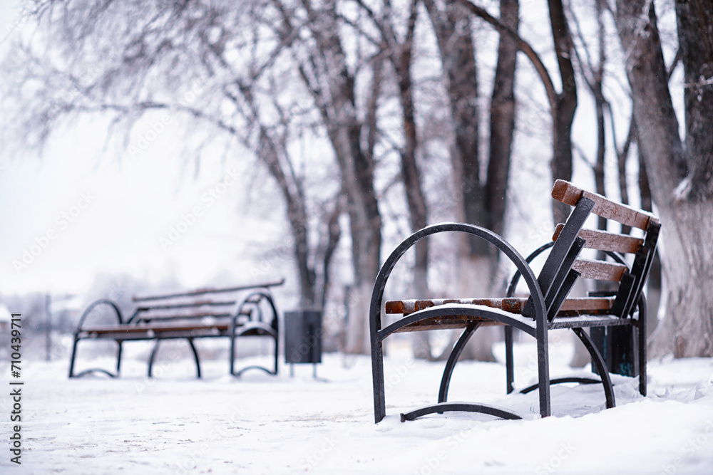 park bench on a winter alley at snowfall. bench with snow after snowstorm or in snow calamity in europe