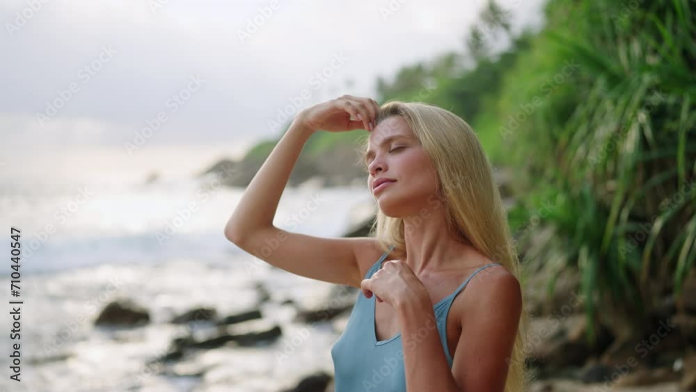 Elegant blonde applies sunscreen on face, enjoys serene sea backdrop. Woman on vacation pampers skin, tropical coast ambiance. Sun protection, skincare routine emphasized. Leisure, showcased. Elegant blonde applies sunscreen on face, enjoys serene sea backdrop. Woman on vacation pampers skin, tropical coast ambiance. Sun protection, skincare routine emphasized. Leisure, showcased.