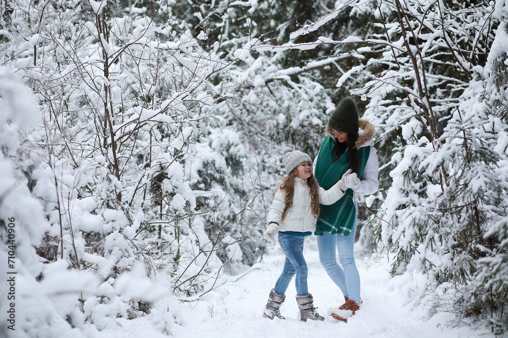 © alexkich - Young family for a walk. Mom and daughter are walking in a winter park.