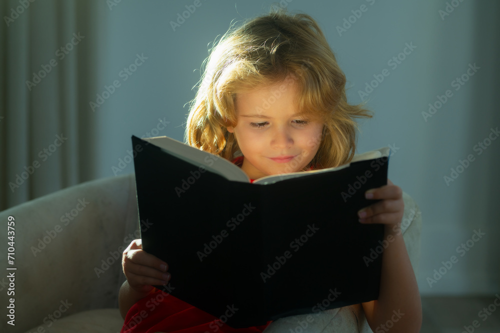 Elementary school nerd boy pupil read book. Little child boy lying on the couch at home and reading a childrens story book. Elementary school nerd boy pupil read book. Little child boy lying on the couch at home and reading a childrens story book.
