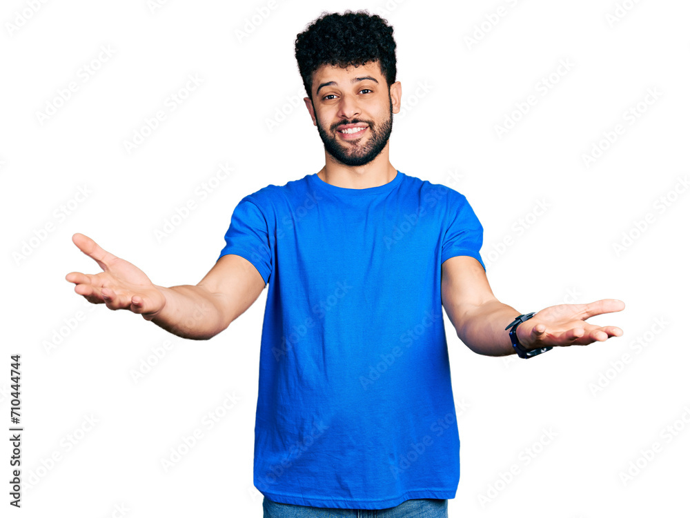 Young arab man with beard wearing casual blue t shirt smiling cheerful offering hands giving assistance and acceptance. Young arab man with beard wearing casual blue t shirt smiling cheerful offering hands giving assistance and acceptance.