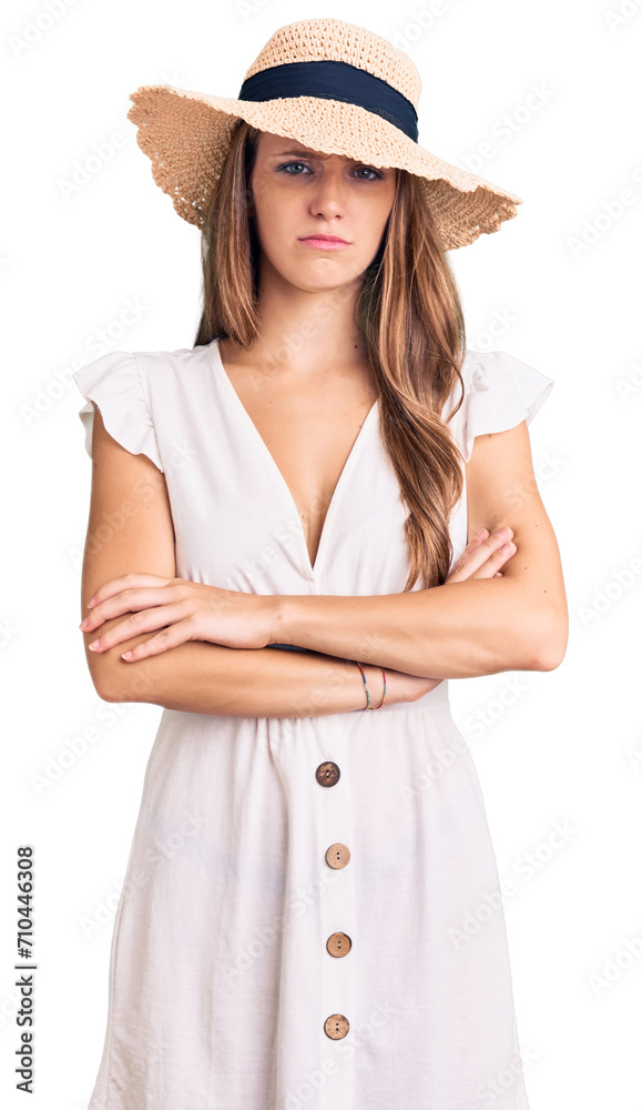 Young beautiful blonde woman wearing summer dress and hat skeptic and nervous, disapproving expression on face with crossed arms. negative person. Young beautiful blonde woman wearing summer dress and hat skeptic and nervous, disapproving expression on face with crossed arms. negative person.