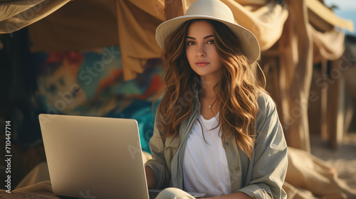 Portrait young brunette woman while sitting at table with laptop working remotely in another country. Remote work concept, digital nomad life concept