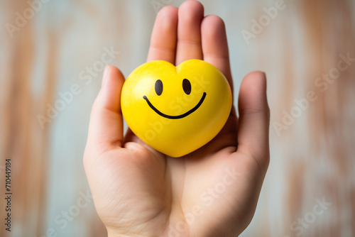 hand holding wooden smiling heart on yellow background