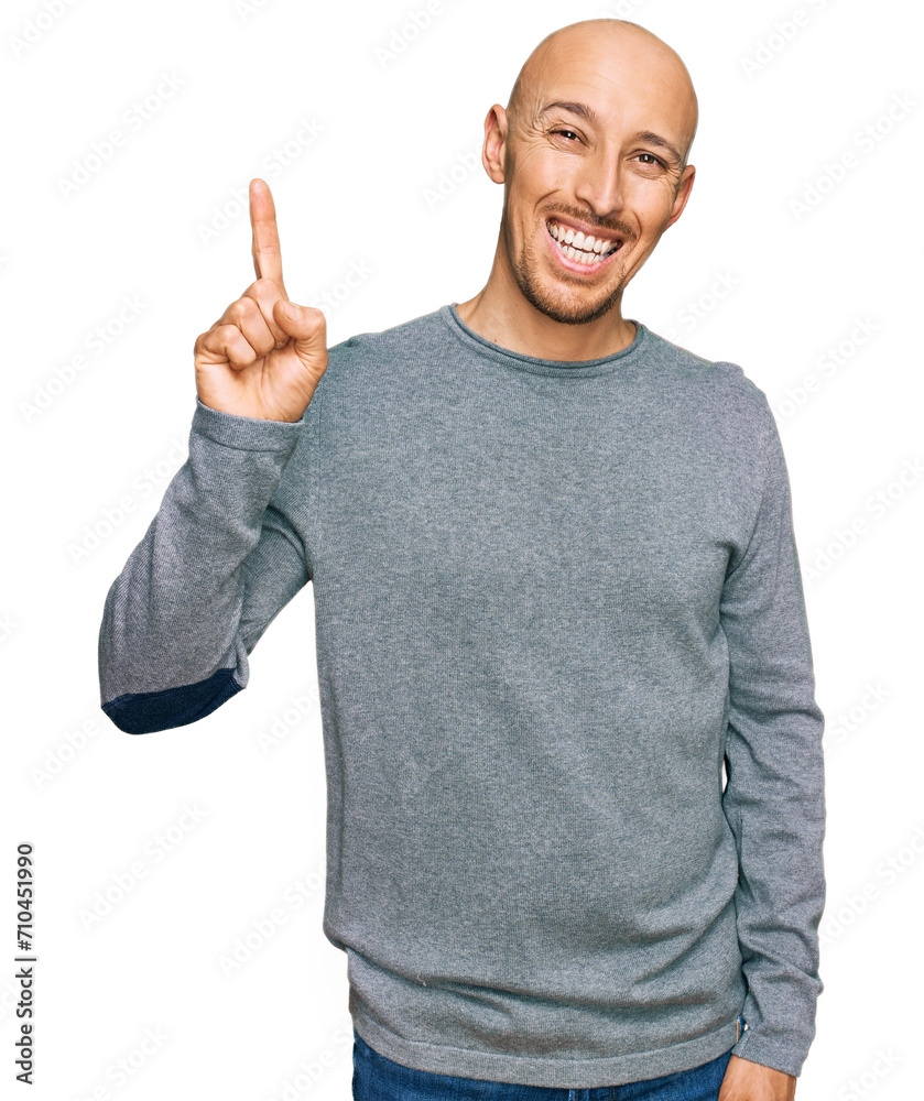Bald man with beard wearing casual clothes showing and pointing up with finger number one while smiling confident and happy.