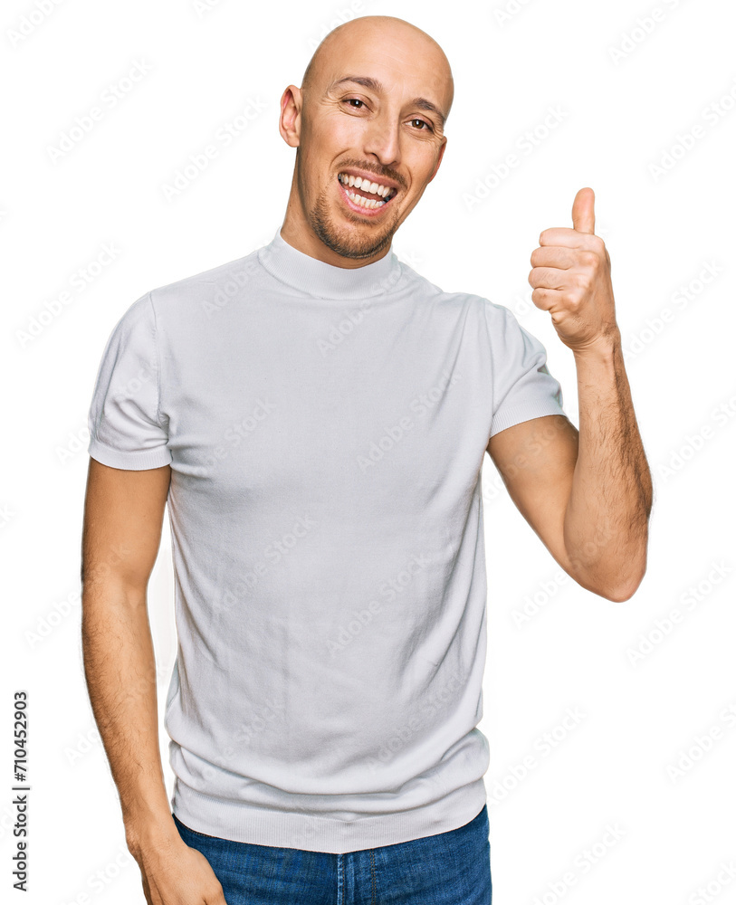 Bald man with beard wearing casual white t shirt smiling with happy face looking and pointing to the side with thumb up. Bald man with beard wearing casual white t shirt smiling with happy face looking and pointing to the side with thumb up.