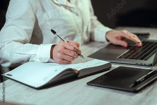 a girl working at a laptop with a phone and a notepad. Online learning, finance, business, remote work. Studying. High quality photo