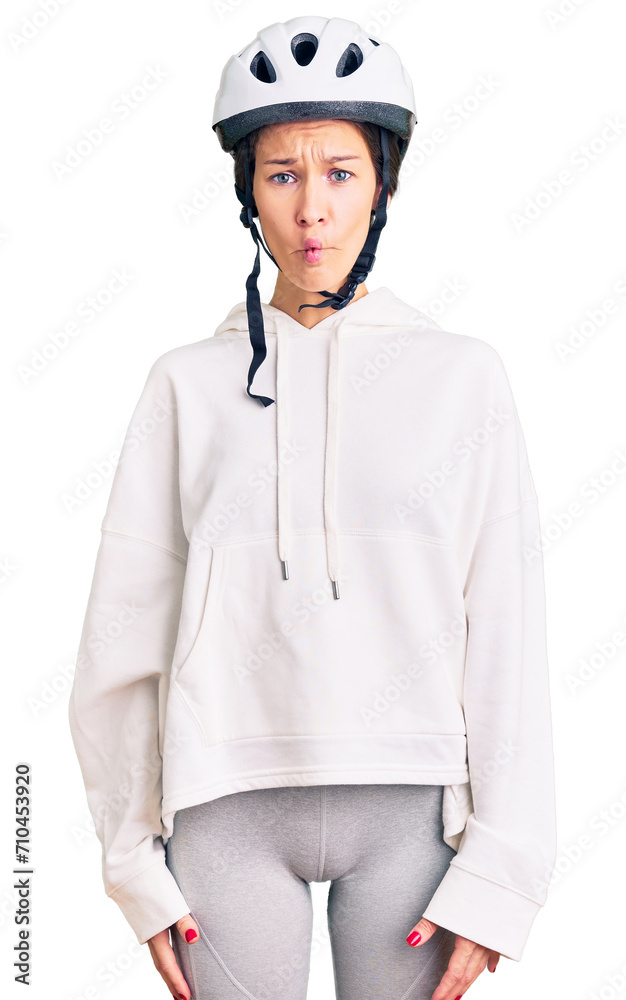 Beautiful brunette young woman wearing bike helmet and sporty clothes making fish face with lips, crazy and comical gesture. funny expression. Beautiful brunette young woman wearing bike helmet and sporty clothes making fish face with lips, crazy and comical gesture. funny expression.