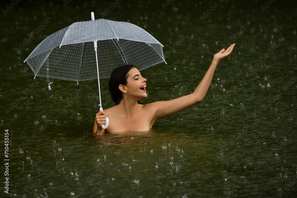 Sexy wet female body. Sexy topless Woman with umbrella in water. Summer rain. Rainy weather. Rain rain go away. Sexy woman sensually relaxing in water. Recreation wellness and wellbeing. Sensual rain.
