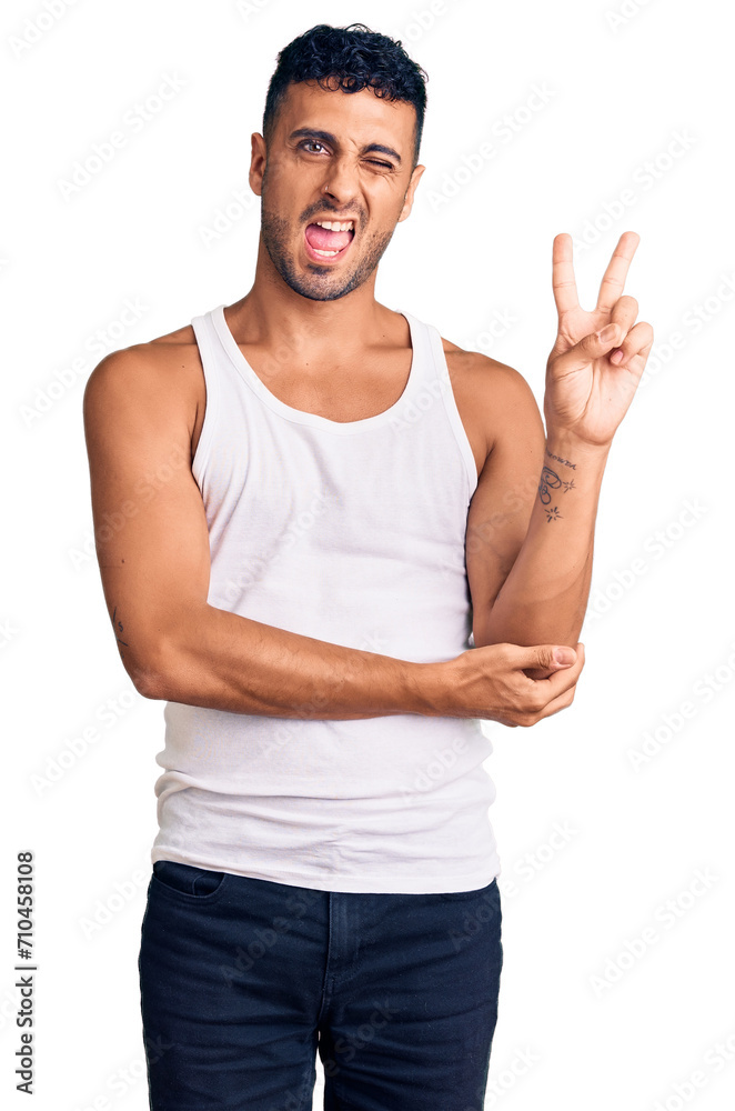 Young hispanic man wearing casual clothes smiling with happy face winking at the camera doing victory sign. number two. Young hispanic man wearing casual clothes smiling with happy face winking at the camera doing victory sign. number two.