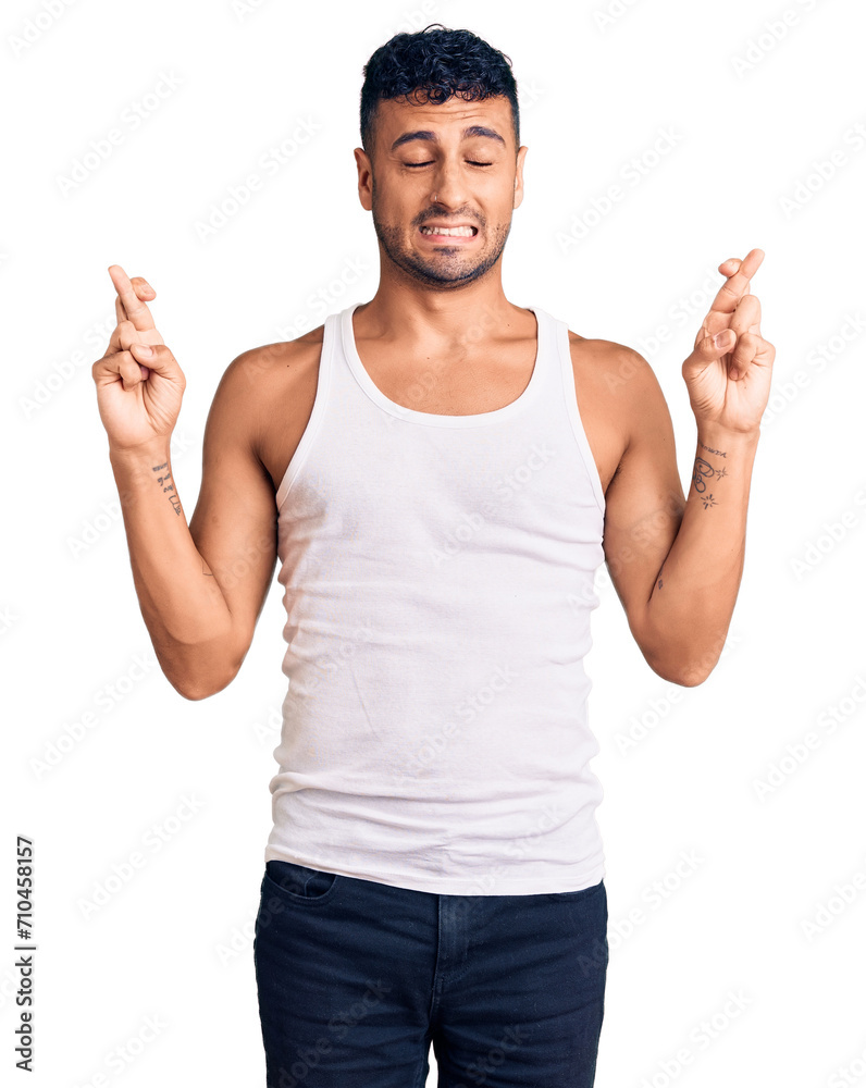 Fototapeta premium Young hispanic man wearing casual clothes gesturing finger crossed smiling with hope and eyes closed. luck and superstitious concept.