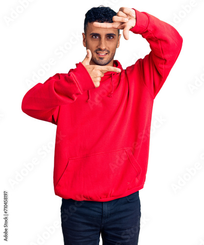 Young hispanic man wearing casual clothes smiling making frame with hands and fingers with happy face. creativity and photography concept. © Krakenimages.com