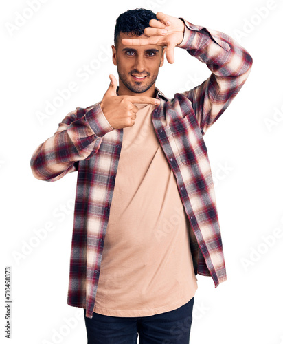 Young hispanic man wearing casual clothes smiling making frame with hands and fingers with happy face. creativity and photography concept.