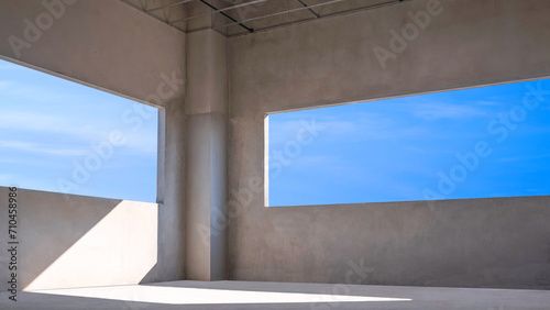 Blue sky view inside of two Panoramic Window Frames with sunlight shining through into incomplete concrete Wall Room of modern House Building Structure in Construction Site