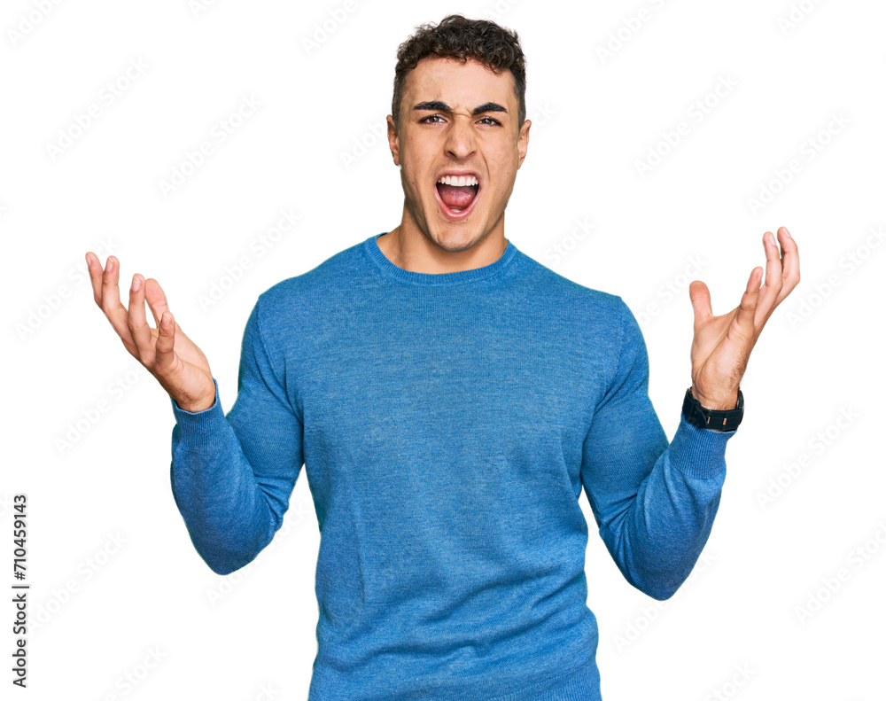 Hispanic young man wearing casual clothes crazy and mad shouting and yelling with aggressive expression and arms raised. frustration concept. Hispanic young man wearing casual clothes crazy and mad shouting and yelling with aggressive expression and arms raised. frustration concept.