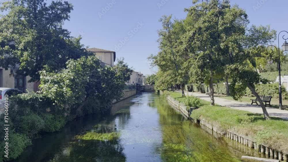 small, wide river in France in a small town by a park in good sunny weather with small stone houses and lots of nature and a bridge small, wide river in France in a small town by a park in good sunny weather with small stone houses and lots of nature and a bridge