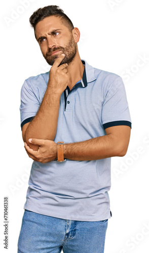 Handsome man with beard wearing casual clothes looking confident at the camera smiling with crossed arms and hand raised on chin. thinking positive.
