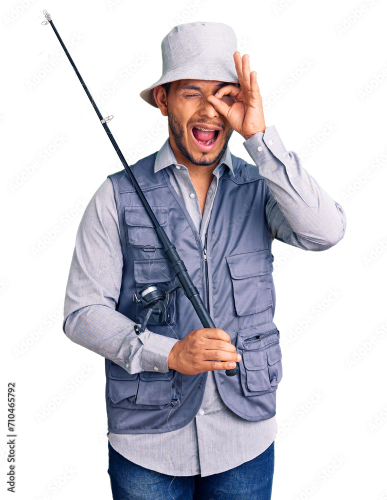 Handsome latin american young man wearing fisherman equipment smiling happy doing ok sign with hand on eye looking through fingers Handsome latin american young man wearing fisherman equipment smiling happy doing ok sign with hand on eye looking through fingers