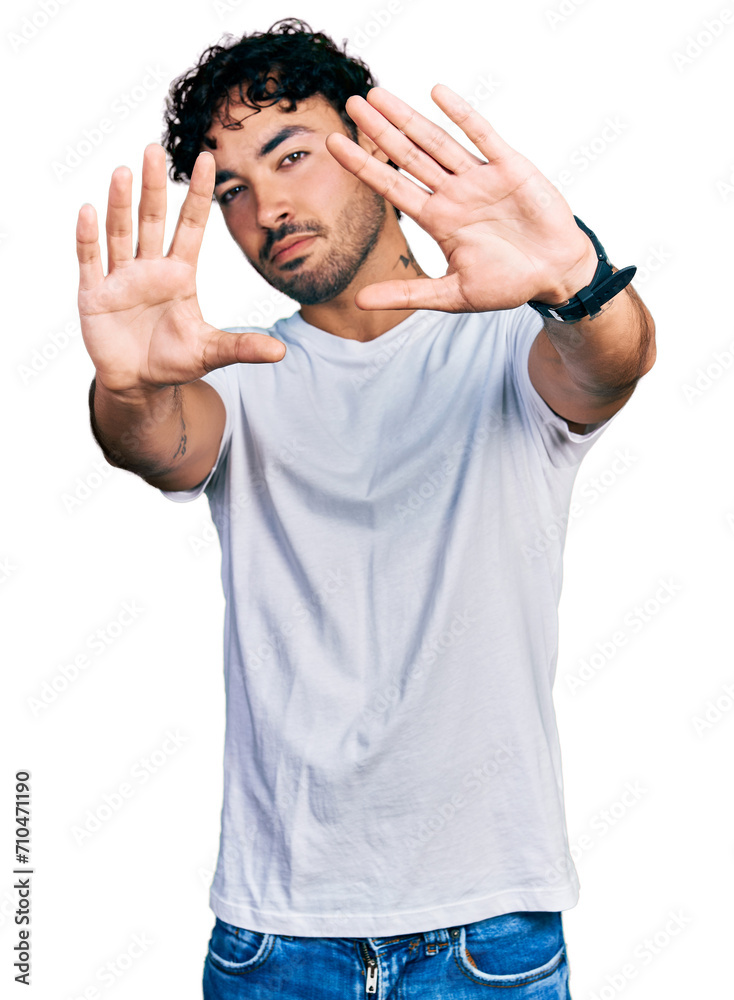 Hispanic young man with beard wearing casual white t shirt doing frame using hands palms and fingers, camera perspective Hispanic young man with beard wearing casual white t shirt doing frame using hands palms and fingers, camera perspective