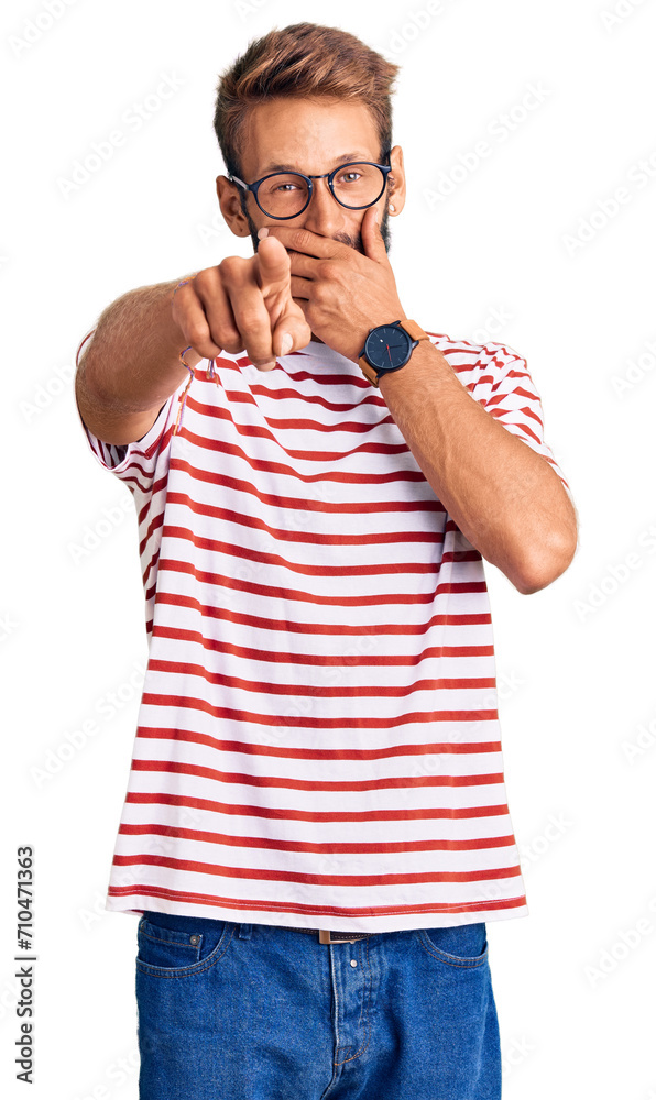Handsome blond man with beard wearing casual clothes and glasses laughing at you, pointing finger to the camera with hand over mouth, shame expression Handsome blond man with beard wearing casual clothes and glasses laughing at you, pointing finger to the camera with hand over mouth, shame expression