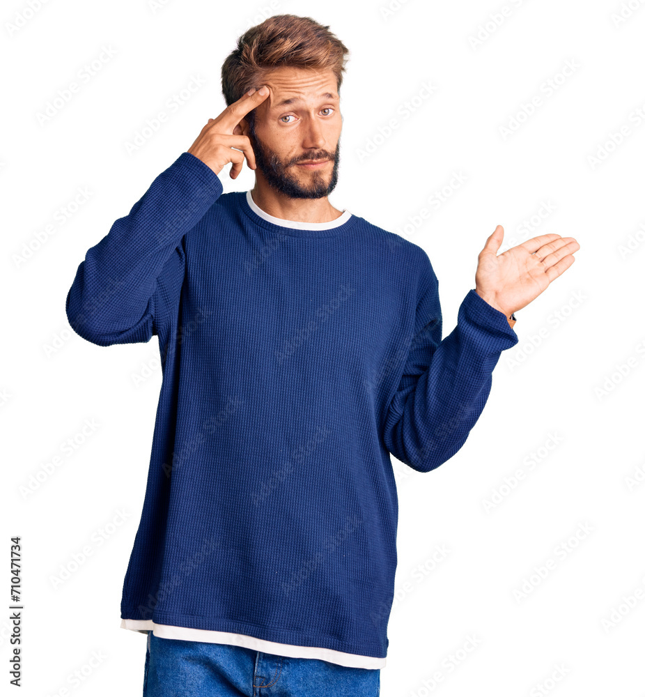 Handsome blond man with beard wearing casual sweater confused and annoyed with open palm showing copy space and pointing finger to forehead. think about it. Handsome blond man with beard wearing casual sweater confused and annoyed with open palm showing copy space and pointing finger to forehead. think about it.