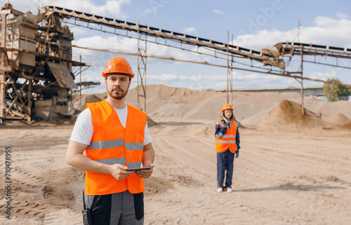 Engineer Worker use computer tablet for control quarry industrial excavator on construction site or open pit mine sand