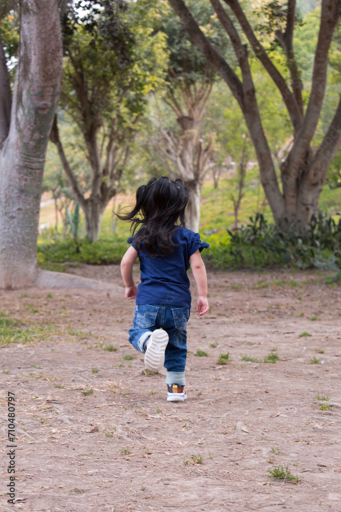 Little kid running sitting down on a park having fun outdoors Little kid running sitting down on a park having fun outdoors