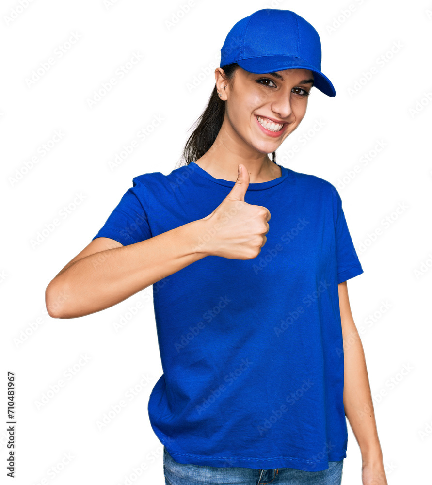 Young hispanic girl wearing delivery courier uniform doing happy thumbs up gesture with hand. approving expression looking at the camera showing success.