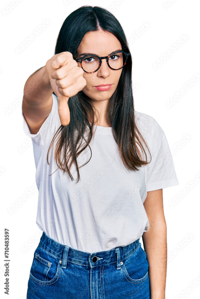 Young hispanic woman wearing casual clothes and glasses looking unhappy and angry showing rejection and negative with thumbs down gesture. bad expression. Young hispanic woman wearing casual clothes and glasses looking unhappy and angry showing rejection and negative with thumbs down gesture. bad expression.
