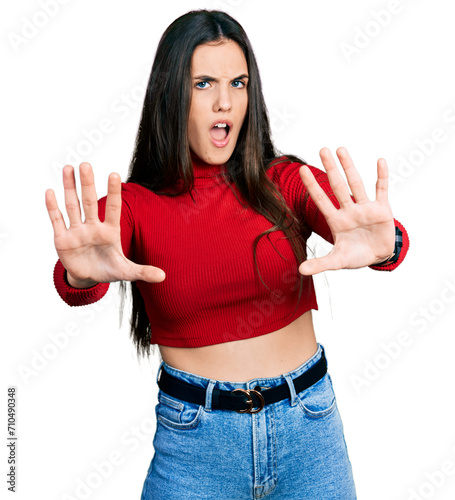 Young brunette teenager wearing red turtleneck sweater doing stop gesture with hands palms, angry and frustration expression