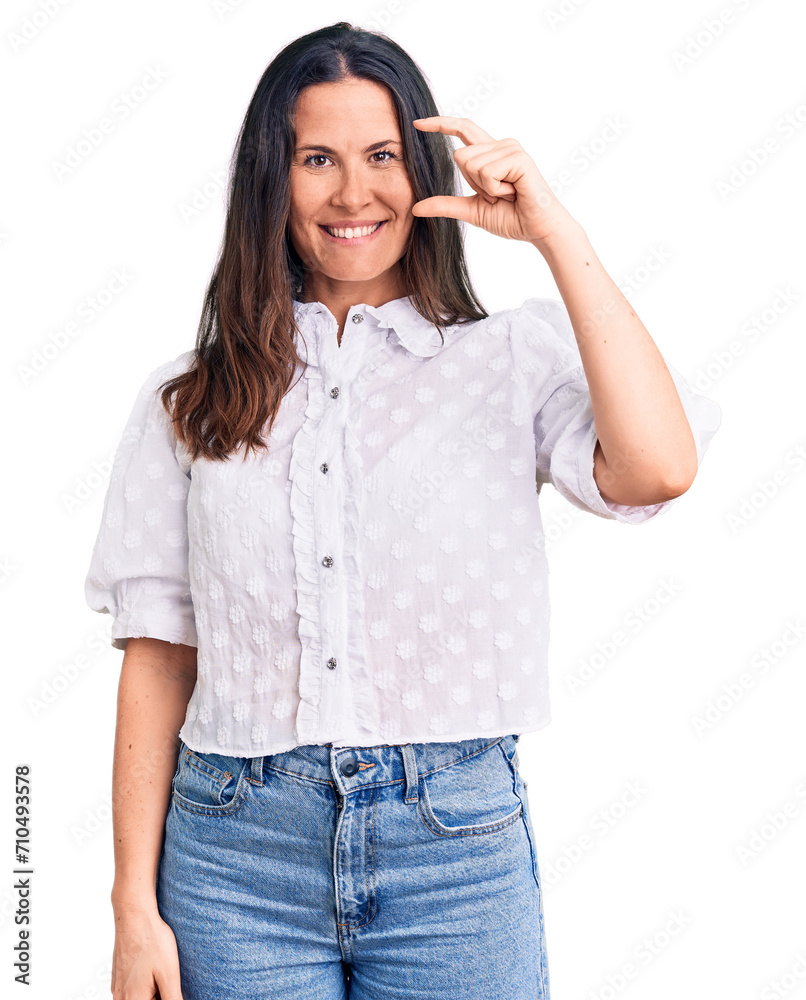 Young beautiful brunette woman wearing casual shirt smiling and confident gesturing with hand doing small size sign with fingers looking and the camera. measure concept.