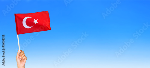 Turkish flag. Hand holding waving the national flag of Turkey against blue sky. 