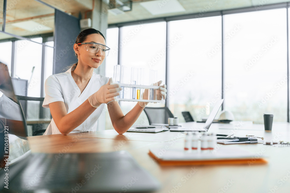 Working with bunch of test tubes. Female doctor in white coat is indoors Working with bunch of test tubes. Female doctor in white coat is indoors