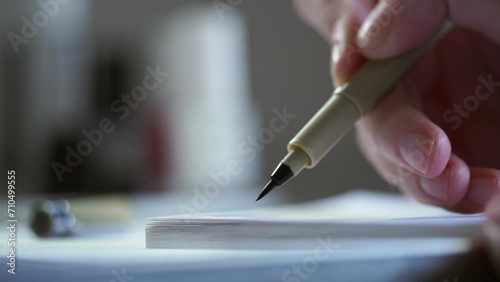 A man signs with a ballpoint pen on a white sheet of paper. Important notes. Office work. Woman hands writing on a piece of paper. Writing essay or letters. Doing homework. photo