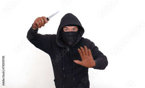 Bad guy in his black hoodie, raising his hand with a knife to threat the victim photo