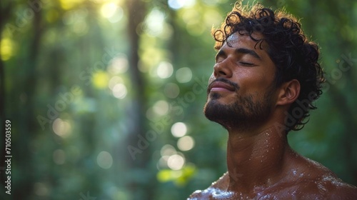 Portrait of a young man with wet hair and closed eyes in the forest.