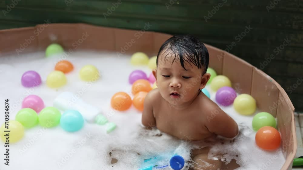 Cute baby having fun taking bath playing in water with foam with colorful toys. Cute baby having fun taking bath playing in water with foam with colorful toys.