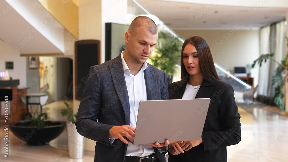 Confident male leader negotiating with business woman, explaining the benefits of a contract in the lobby, advising a corporate client presenting a business proposal.