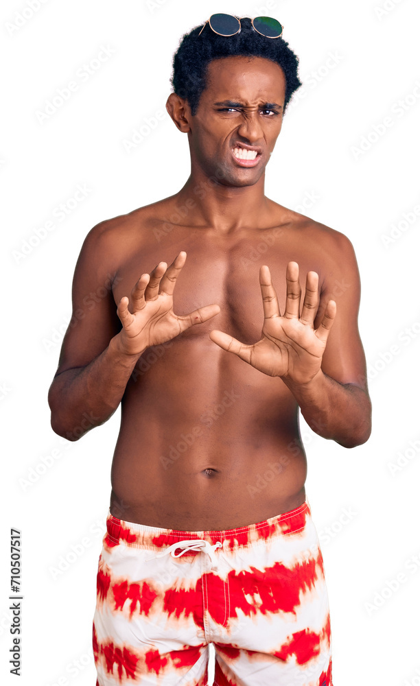 Fototapeta premium African handsome man wearing swimsuit and sunglasses disgusted expression, displeased and fearful doing disgust face because aversion reaction. with hands raised