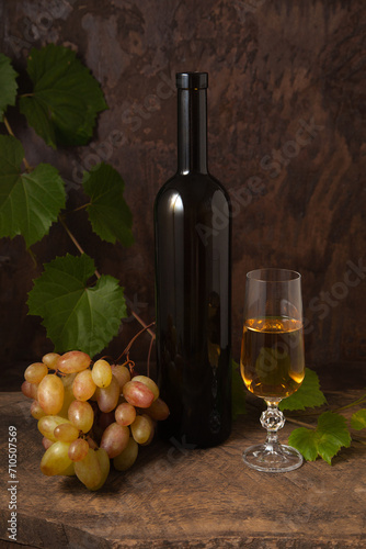 Still life with glass of white wine and grapes on vintage wooden background..