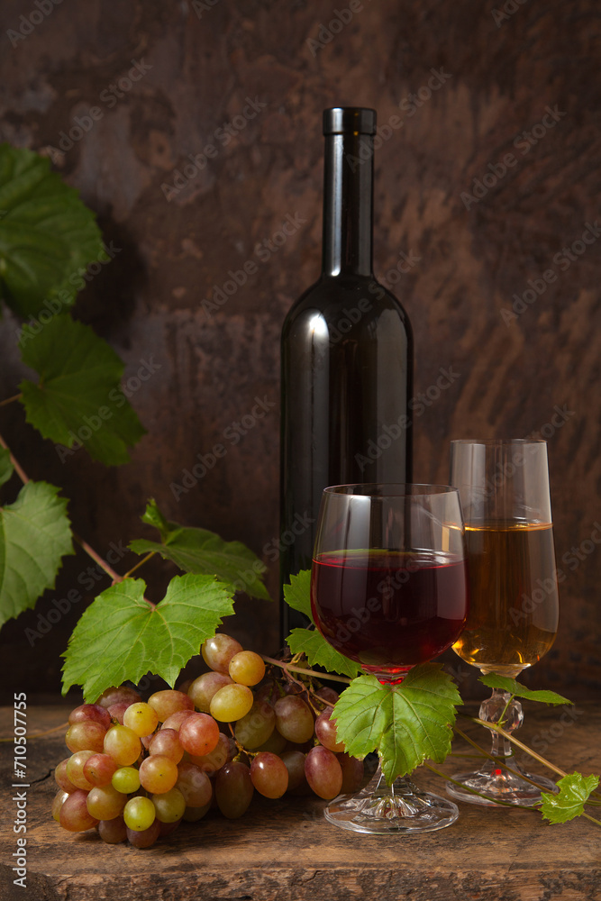 Still life with glasses of red and white wine and grapes on vintage wooden background..