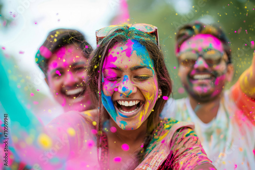 Laughing beautiful woman with her friends throws up colourful powders on Holi celebration festival. 