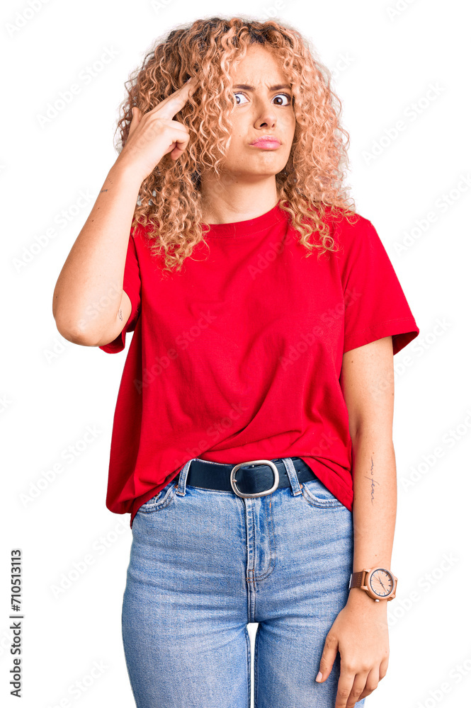 Young blonde woman with curly hair wearing casual red tshirt shooting and killing oneself pointing hand and fingers to head like gun, suicide gesture.