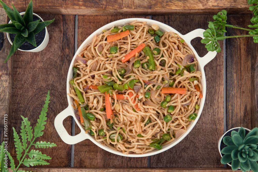 Tasty Vegetable hakka noodles in white plate and isolated background. Indo-Chinese vegetarian cuisine dish. Indian veg noodles with vegetables. Classic Asian meal - obrazy, fototapety, plakaty 